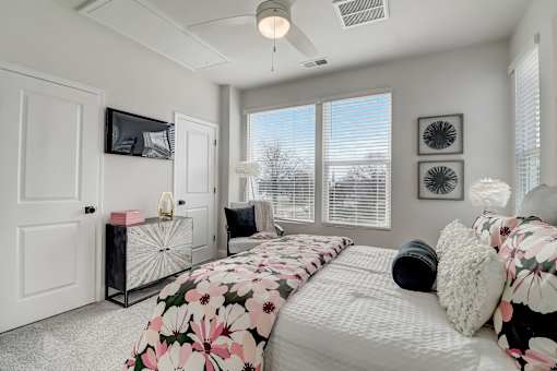A bedroom with a large bed and a TV on the wall.