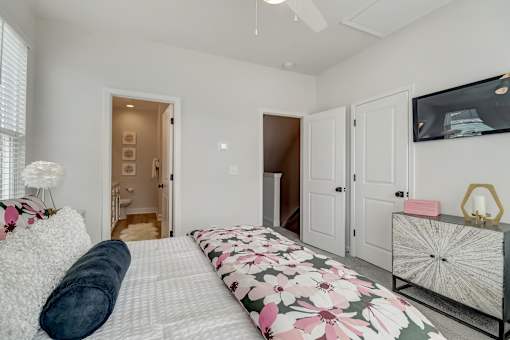 A bedroom with a large bed and a television on the wall.