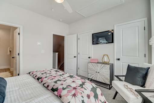 A bedroom with a bed, a couch, and a TV mounted on the wall.