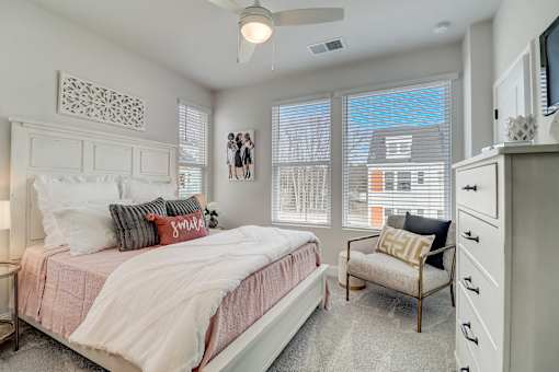 A bedroom with a bed, chair, and a ceiling fan.