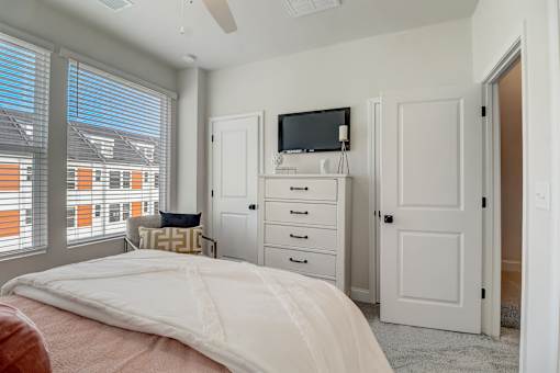 A bedroom with a bed, dresser, and television.