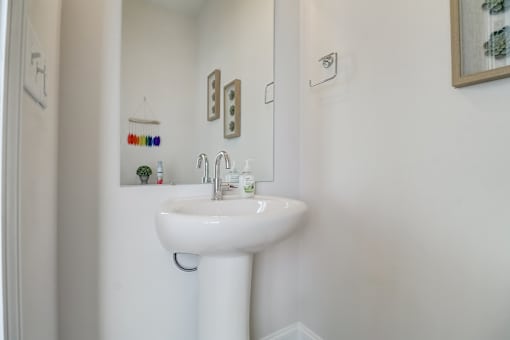 A white pedestal sink in a bathroom with a mirror above it.