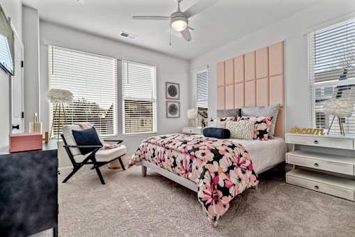 A bedroom with a bed, chair, and a ceiling fan.
