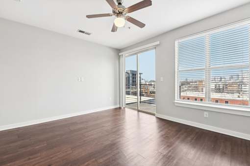 A room with a ceiling fan and sliding glass doors.