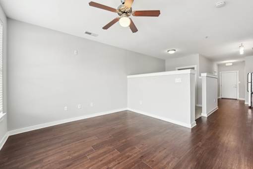 A room with a ceiling fan and wooden flooring.