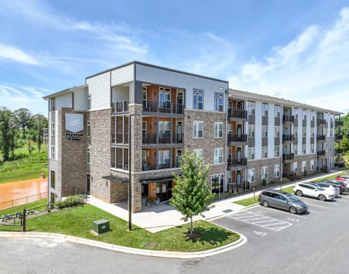 A modern apartment complex with a parking lot in front.