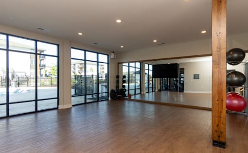 A gym with a wooden floor and a large mirror on the wall.