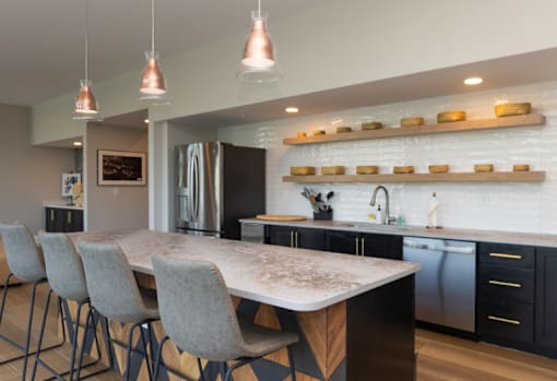 A modern kitchen with a large island and grey chairs.
