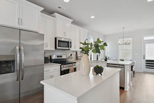 A modern kitchen with a stainless steel refrigerator and white cabinets.