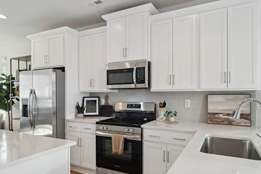 A modern kitchen with white cabinets and stainless steel appliances.