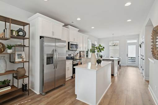 A modern kitchen with a refrigerator, microwave, and oven.