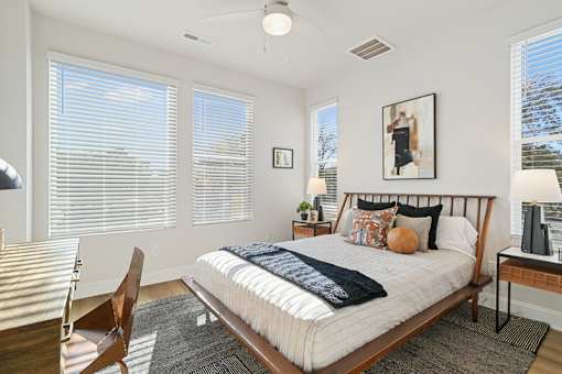 A bedroom with a bed, chair, and window with blinds.