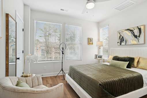 A bedroom with a bed, chair, and window with blinds.