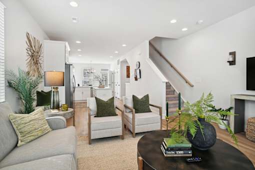 A living room with a grey couch, a coffee table, and a staircase.