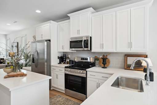 A modern kitchen with white cabinets and stainless steel appliances.
