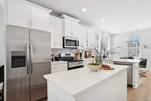 A modern kitchen with a stainless steel refrigerator and white countertops.