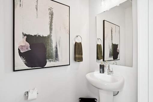 A bathroom with a white sink and a large abstract painting above it.