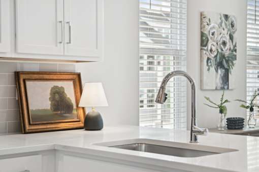 A kitchen with a white countertop and a framed picture of a tree.