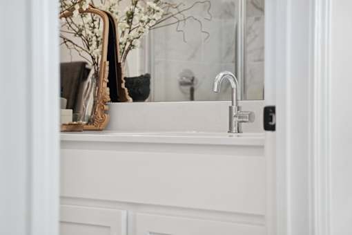 A white sink with a silver faucet and a plant on the counter.