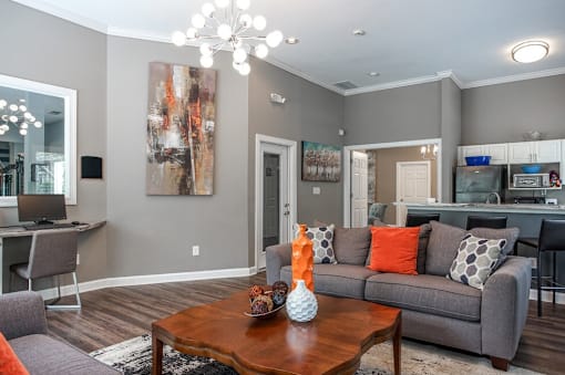 A modern living room with a grey couch, a wooden coffee table, and a large abstract painting on the wall.