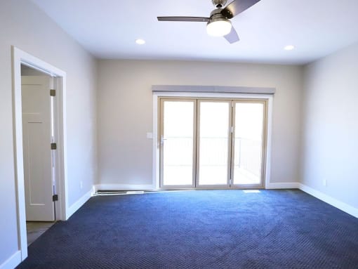 Spacious Bedroom With Carpeted Flooring, Fan and Light Fixture, and Plenty of Natural Light at Moenave Townhomes in Springdale, Utah