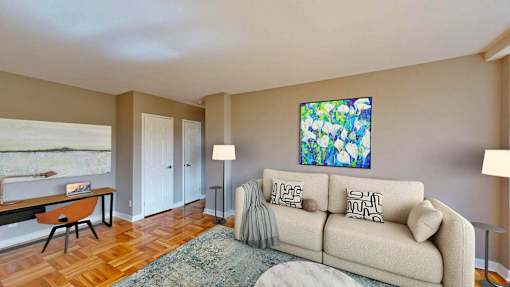 A living room with a couch, a chair, a painting, and a lamp.