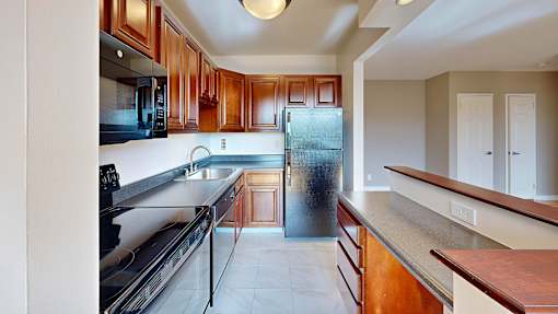 A kitchen with wooden cabinets and a black fridge.