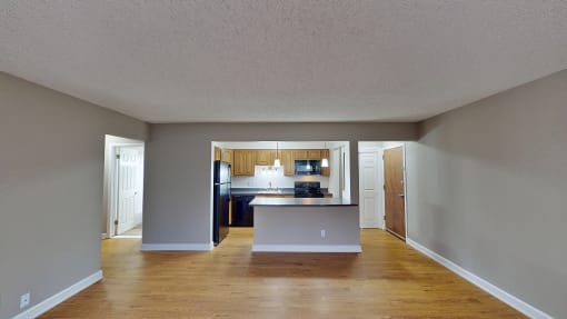 an empty living room and kitchen with wood floors