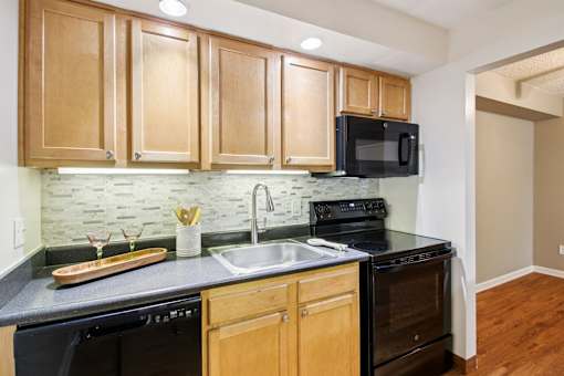 A kitchen with wooden cabinets and black appliances.