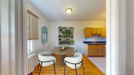 A kitchen with a table and chairs in the foreground and a countertop with a sink in the background.