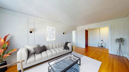 A living room with a white couch and a glass coffee table.
