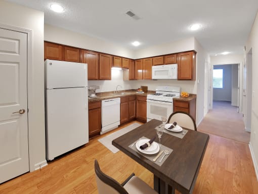 a kitchen with white appliances and wooden cabinets and a dining table