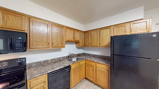 A kitchen with black appliances and wooden cabinets.