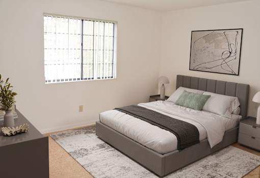 A bedroom with a large bed and a framed picture on the wall.