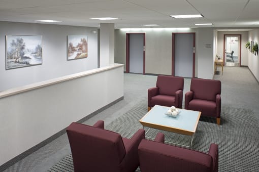 an empty waiting room with red chairs and a table