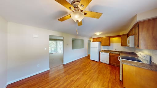an empty living room with a ceiling fan and a kitchen