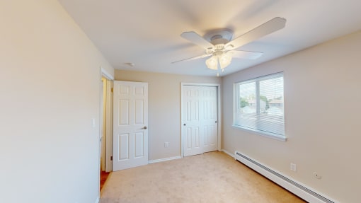 an empty bedroom with a ceiling fan and a window
