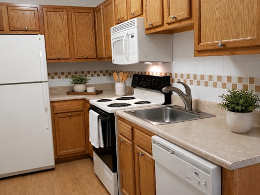 A kitchen with white appliances and wooden cabinets.