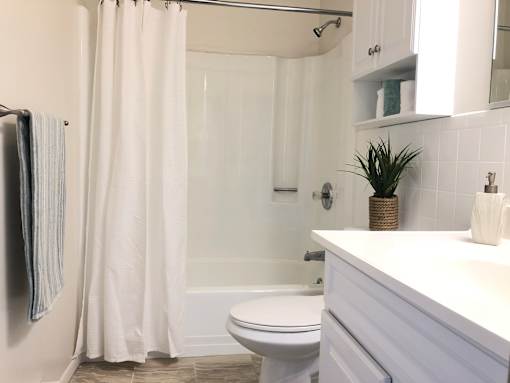 A white bathroom with a toilet, sink, and shower.