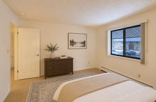 A bedroom with a large bed, a dresser, and a window.