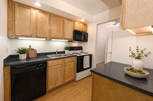 A kitchen with wooden cabinets and black countertops.