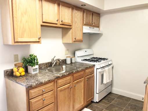 A kitchen with a white stove and wooden cabinets.