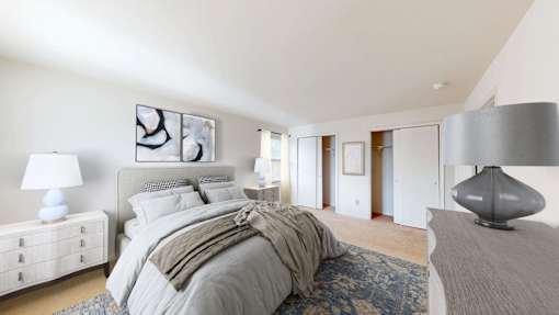 A bedroom with a large bed and a grey lamp.