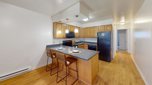 a kitchen with an island and wooden cabinets and a black refrigerator