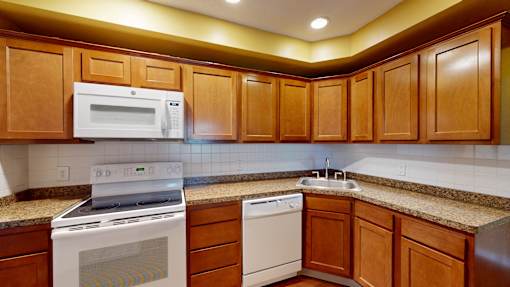 A kitchen with wooden cabinets and a white microwave above the stove.