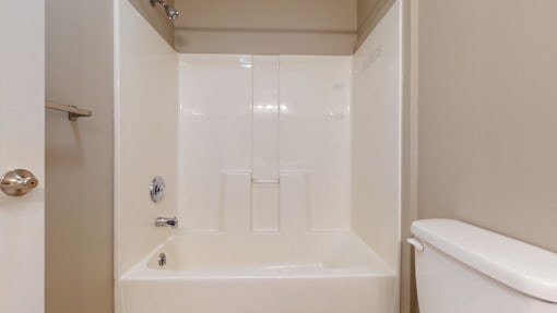 A white bathroom with a tub and toilet.
