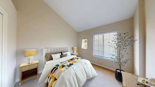 A bedroom with a large bed and a small tree.