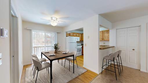 A dining room with a table set for two and a kitchen in the background.