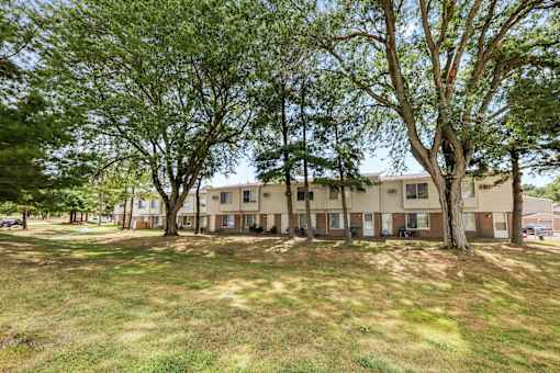 A grassy area with trees and apartment buildings in the background.