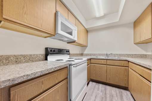 A kitchen with a white stove and microwave above it.